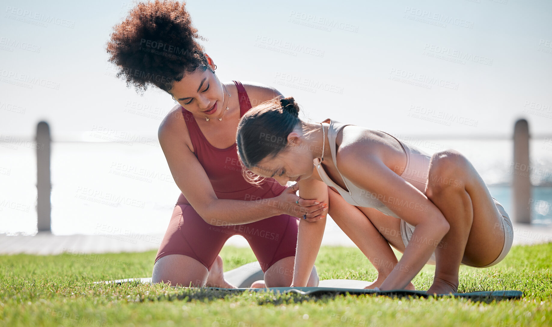 Buy stock photo Yoga class, personal trainer or women support, helping and learning balance, training and exercise on beach or park. Coaching black woman with pilates workout on grass for sports and body wellness