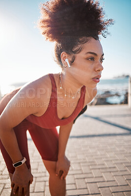 Buy stock photo Fitness, music and tired with a black woman runner on the promenade for cardio or endurance training. Exercise, running and earphones with a sports person feeling exhausted during her workout