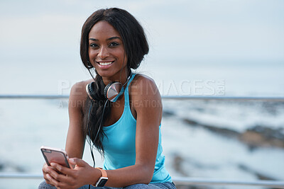Buy stock photo Smartphone, beach and portrait of black woman with music, headphones or technology for fitness break on blue sky. Young USA person on phone for social media, mental health and audio streaming by sea
