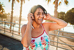 Headphones, senior woman and laughing of a elderly person in Miami happy from summer holiday. Beach, music listening and web audio streaming of a old female with happiness on vacation in retirement
