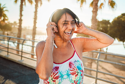 Buy stock photo Headphones, senior woman and laughing of a elderly person in Miami happy from summer holiday. Beach, music listening and web audio streaming of a old female with happiness on vacation in retirement