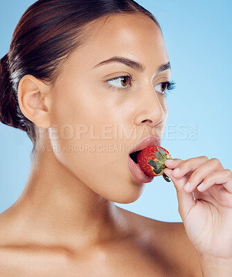 Buy stock photo Strawberry, woman and fruit of a model eating healthy food for diet and skincare health. Blue background, studio and young person with nutrition and clean eating for wellbeing and vitamin c skin glow