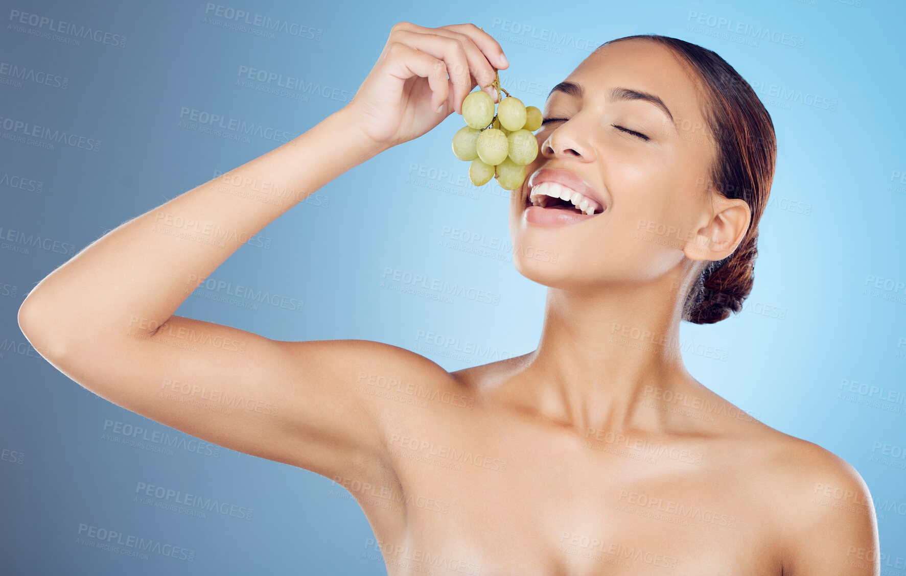 Buy stock photo Grapes, skincare and woman in studio for wellness, detox or organic treatment on blue background. Fruit, snack and girl model with relax during beauty, routine and happy with organic product isolated