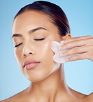 Woman, beauty and face massage with gua sha, facial product or aesthetic skincare in studio. Young model, crystal stone tools and wellness for natural cosmetics, rose quartz dermatology or body salon