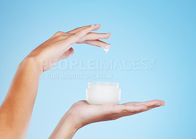 Buy stock photo Skincare, beauty and hands with face cream in studio for a natural, cosmetic or hydration skin routine. Self care, product and closeup of female with spf, sunscreen or facial creme by blue background