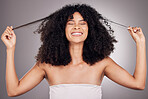 Hair in hands, beauty and face of black woman for wellness, natural growth and curly style. Salon, luxury cosmetics and happy girl smile holding strand for keratin treatment result on gray background