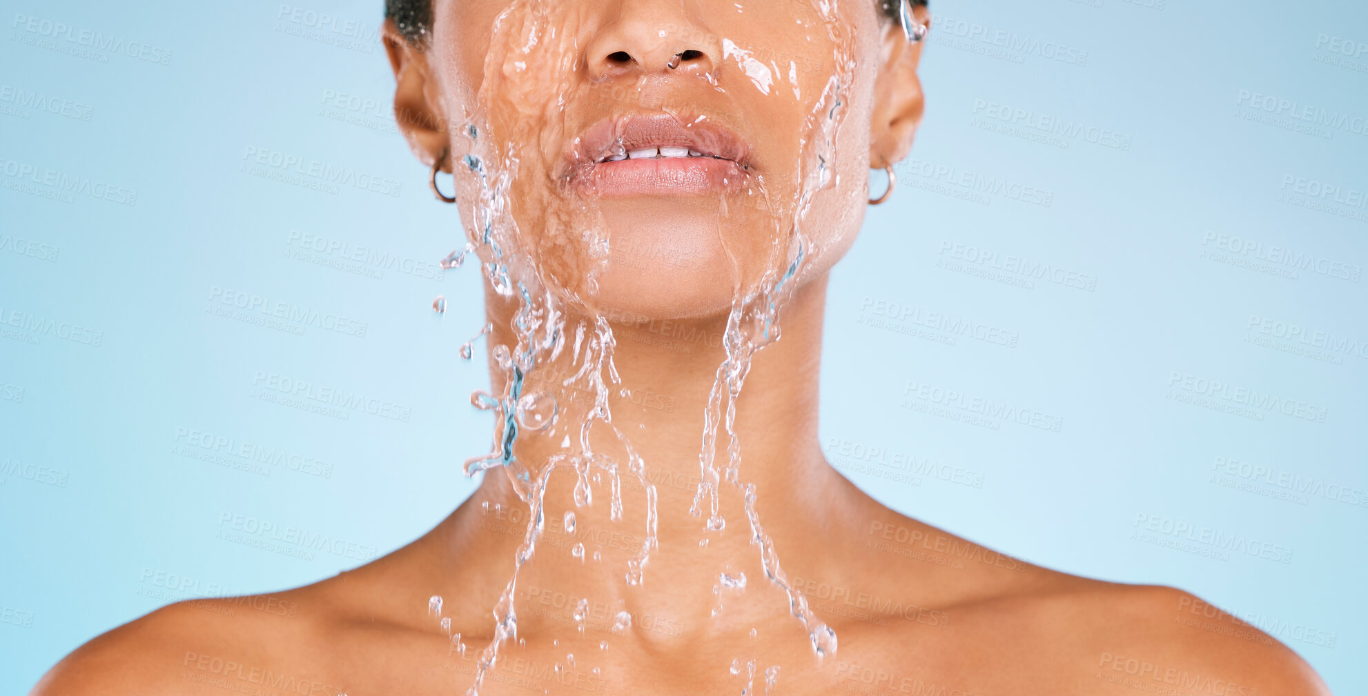 Buy stock photo Face, water and cleaning with a black woman in studio on a blue background for hygiene or hydration. Splash, shower and bathroom with a young female washing her body for natural skincare or wellness