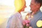 Couple, sparkler and date to celebrate love, birthday and vacation or holiday at beach in summer. Senior man and woman hug outdoor with star and bokeh for sunset dating, marriage or valentines day