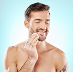 Skincare, cotton pad and man in a studio for health, grooming and hygiene facial routine. Beauty, wellness and handsome male model doing a fresh morning face treatment isolated by a blue background.