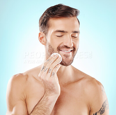 Buy stock photo Skincare, cotton pad and man in a studio for health, grooming and hygiene facial routine. Beauty, wellness and handsome male model doing a fresh morning face treatment isolated by a blue background.