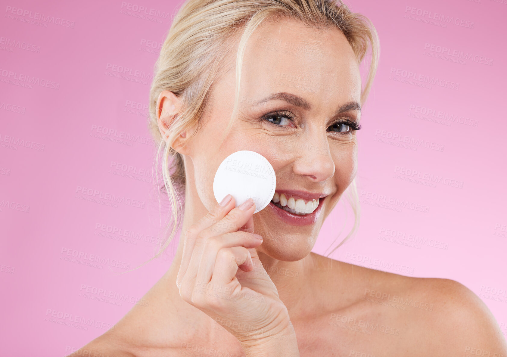 Buy stock photo Beauty, cotton and portrait of woman cleaning her face with dermatology cosmetics in studio. Happy aesthetic person on pink background with pad for detox, self care and facial makeup for wellness