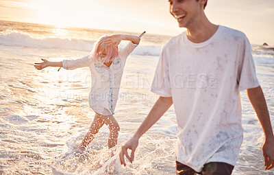 Buy stock photo Couple at beach, splash in water with ocean, travel and freedom outdoor, love and care in relationship with youth. Cafe free at sunset, nature and sea waves with young people on holiday in Hawaii