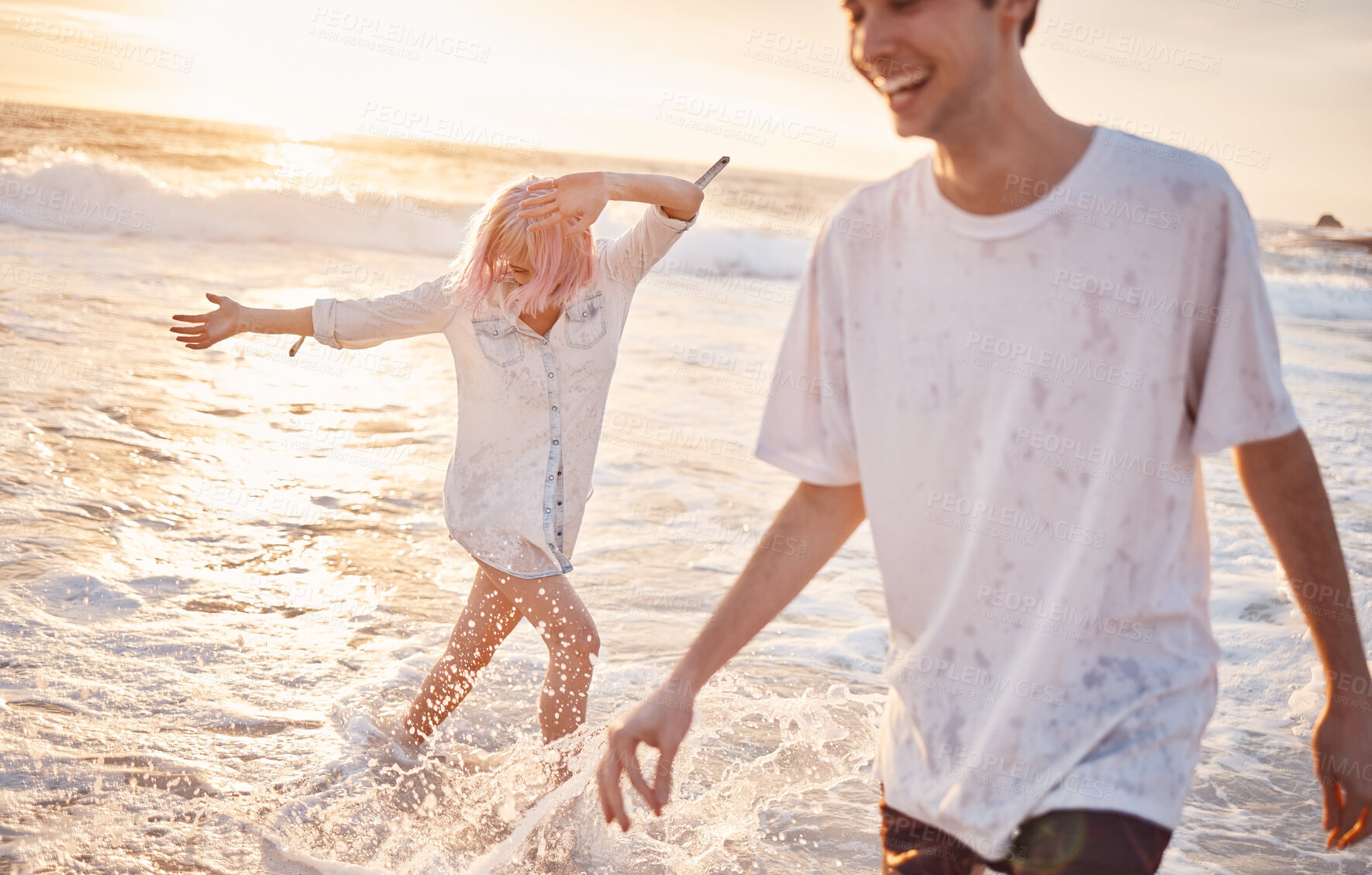 Buy stock photo Couple at beach, splash in water with ocean, travel and freedom outdoor, love and care in relationship with youth. Cafe free at sunset, nature and sea waves with young people on holiday in Hawaii