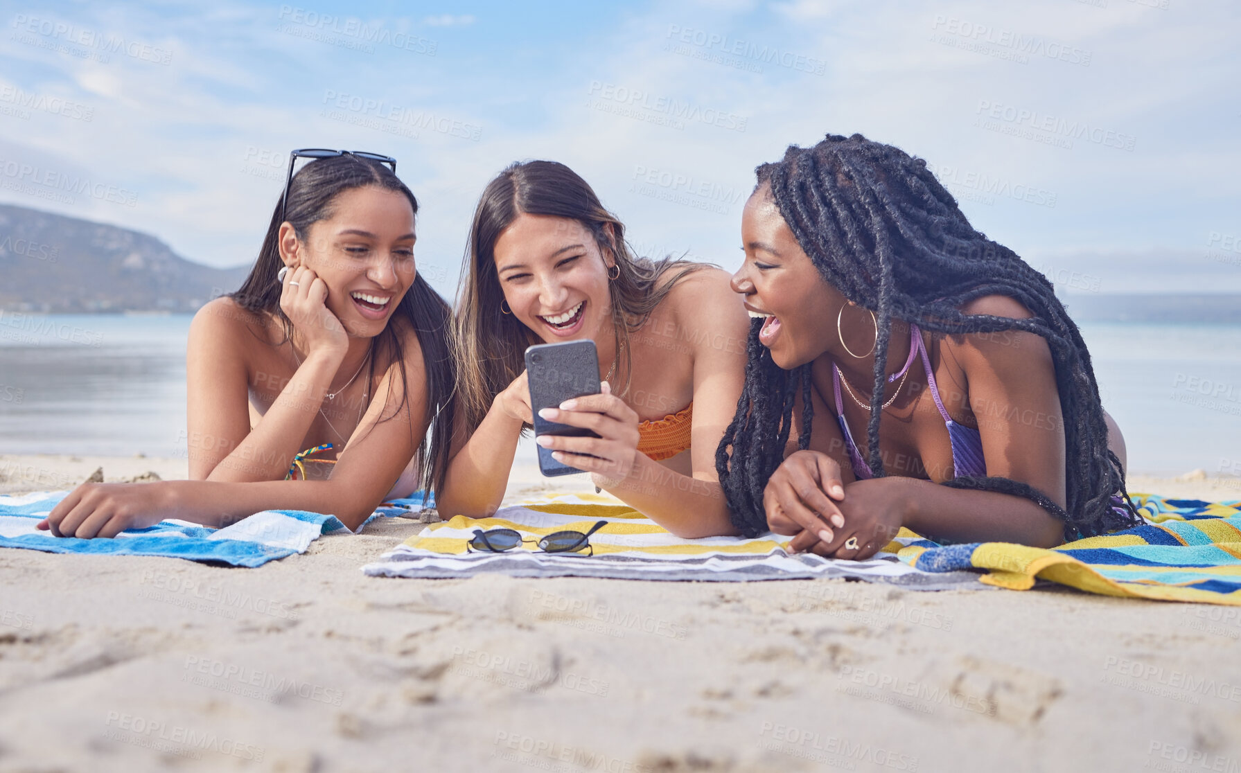 Buy stock photo Girl friends, beach and phone of a teenager laughing at funny meme by the sea in Miami. Travel, vacation and sunshine with happy students enjoying spring break with mobile connection lying on sand 