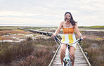 Portrait, bike and mockup with a woman cycling outdoor in nature for freedom, fun or adventure in the countryside. Happy, smile and bicycle with a female cyclist outside in the wilderness for travel