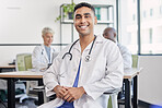 Young doctor, man and portrait at hospital desk with smile for healthcare, planning surgery and teamwork. Leader, doctors and expert vision in health, wellness and happy in clinic with group at table