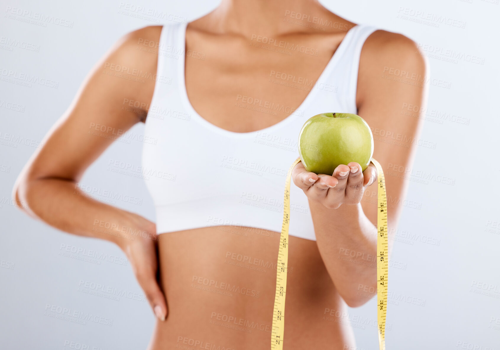 Buy stock photo Diet, apple and tape measure with a fitness black woman in studio on a gray background for healthy eating. Exercise, fruit and wellness with a female posing to promote a lifestyle of health or detox