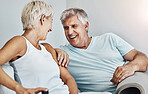 Love, laugh and retirement with a senior couple sitting in the living room of their home together. Happy, smile or relax with a mature man and woman laughing while bonding on the couch in a house