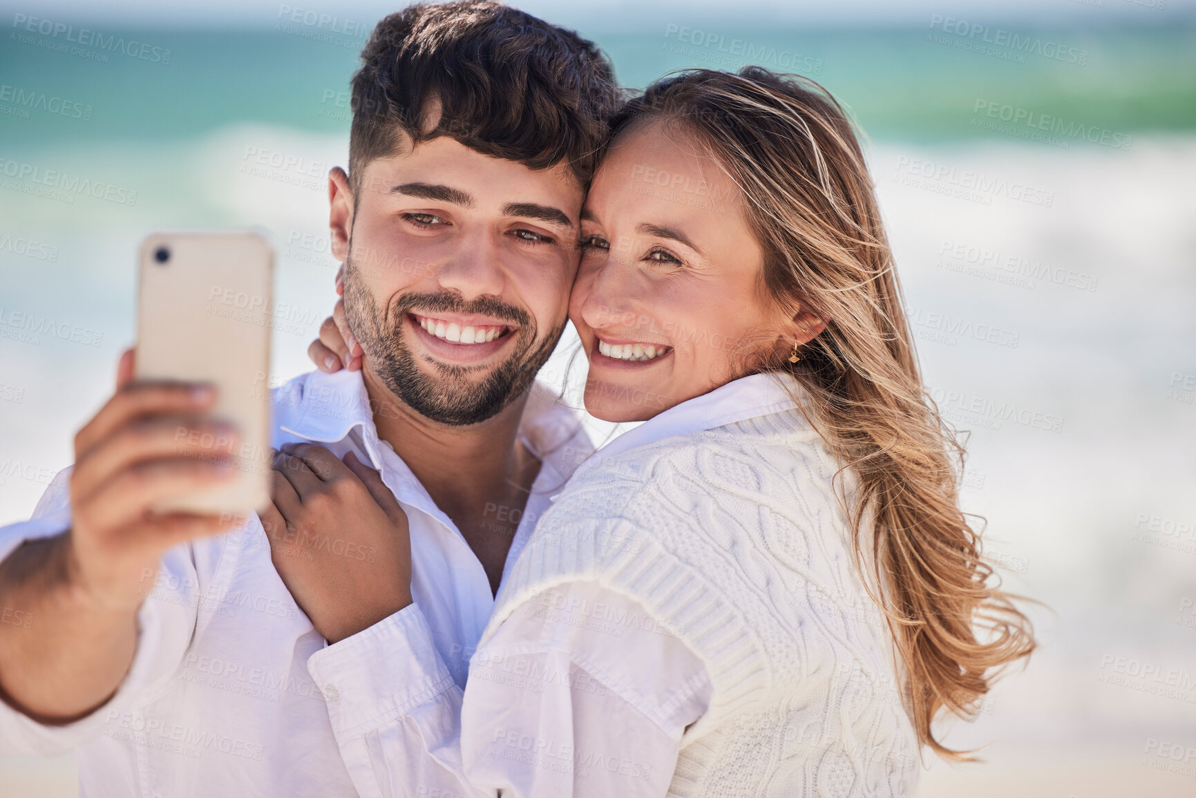 Buy stock photo Beach, love and happy couple taking a selfie while on a date for valentines day, romance or anniversary. Happiness, smile and young man and woman hugging while taking picture by the ocean on vacation
