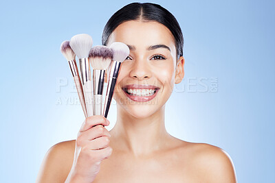 Buy stock photo Beauty brushes, makeup and portrait of woman with smile on blue background for cosmetics, powder and foundation. Skincare, cosmetology and face of girl with brush for application, eyeshadow and salon