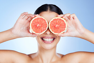 Buy stock photo Woman, hands and fruit with smile for skincare nutrition, vitamin C or healthy diet against a blue studio background. Hand of female holding organic grapefruit for citrus health or beauty wellness