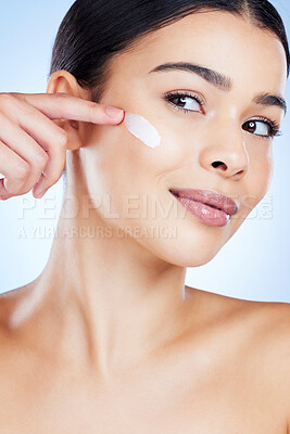 Buy stock photo Woman, face and apply skincare moisturizer in cosmetics or beauty against a blue studio background. Female applying product, lotion or cream for facial treatment, collagen or healthy self care skin