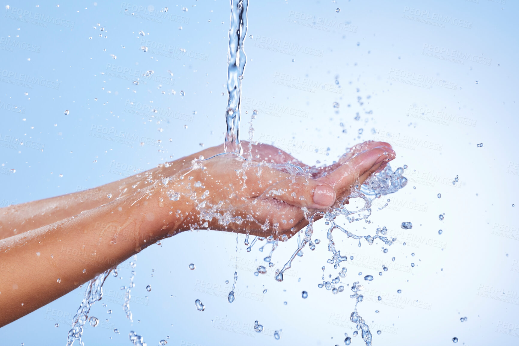 Buy stock photo Hands, water splash and wash for skincare hygiene or hydration against a blue studio background. Closeup of hand with liquid drops, shower or washing for clean wellness or natural sustainability