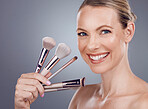 Face, tools for makeup and woman with smile, beauty and skin glow, portrait and foundation on studio background. Powder, cosmetics brush and skincare with shine, cosmetology and cosmetic care