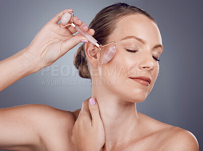 Buy stock photo Woman, face roller and beauty of facial product of aesthetic skincare massage in studio. Female model, rose quartz treatment and wellness for natural cosmetics, crystal stone dermatology or salon spa
