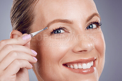 Buy stock photo Eyebrows, cosmetic and portrait of a woman with a tweezers isolated on a grey studio background. Beauty, treatment and happy model plucking hair from face for shaping and grooming on a backdrop