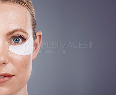 Buy stock photo Skincare mask, eyes and portrait of woman on gray background for wellness, cosmetics and facial care. Salon mockup space, dermatology and half face with pads for anti aging, makeup and beauty product