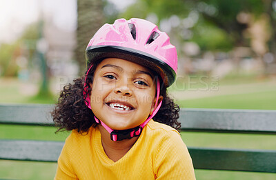 Buy stock photo Girl child, portrait and helmet while happy outdoor on a park bench with a smile for safety gear. Face of black kid in nature learning to ride a bicycle while on summer vacation or holiday for health