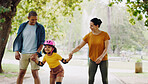 Parents, park and holding hands to rollerskate with girl child with care, learning and support. Interracial family, black man and woman with kid, smile and helping hand on road for outdoor holiday