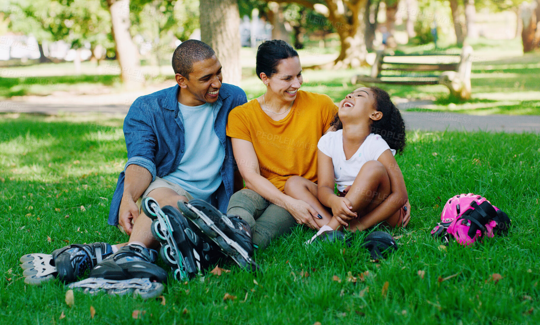 Buy stock photo African family, girl and park with rollerblades, interracial bonding and laugh for comic joke, happy or holiday. Black man, woman and child with happiness, care and diversity on grass for vacation
