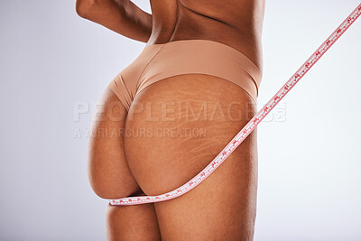 Buy stock photo Woman, ass and tape measure in body care, underwear or weight loss cellulite against a gray studio background. Female buttocks measuring size in lingerie for fitness, diet or healthcare wellness