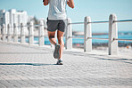 Fitness, legs and man running by ocean in action for wellness, run performance and athlete endurance. Movement, motivation and male runner by sea for exercise, marathon training and cardio workout