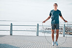 Skipping rope, mockup and man training by the beach for his outdoor morning exercise, workout and fitness routine. Athlete, cardio and male jumping by the ocean or sea for wellness lifestyle