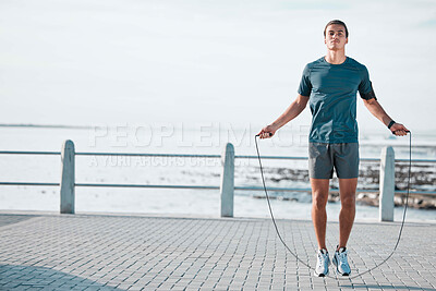 Buy stock photo Skipping rope, mockup and man training by the beach for his outdoor morning exercise, workout and fitness routine. Athlete, cardio and male jump by the ocean or sea for wellness lifestyle