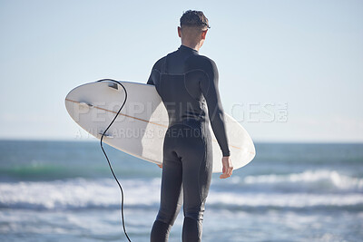 Back, surfing man and standing at beach with board, freedom and summer waves with blue sky. Surfer guy at sea, sunshine and travel for water sports, adventure and ocean in nature