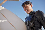 Man, surfing and water shower at beach on face, smile or blue sky in summer, sunshine or ocean travel. Happy surfer cleaning body at tap for sea sports, relax holiday or vacation adventure in wetsuit