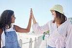 Diversity, friends and high five in support of travel, vacation and summer vacation at a beach. Hands, connecting and women celebrating good news, decision or freedom against blue sky background