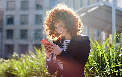 Buy stock photo Business woman, phone and smile for communication, social media or texting and chatting in city. Happy female ginger typing and smiling on smartphone for 5G connection, mobile app or networking