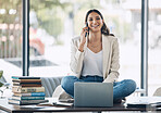 Woman, laptop and phone call and sitting on desk in relax startup, marketing company or advertising business. Smile, happy and talking worker on mobile communication technology, laptop or books study