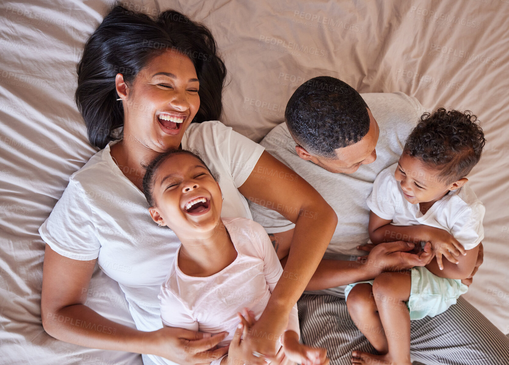 Buy stock photo Top view, love and black family in bedroom, playful and cheerful on weekend break, quality time or happiness. African American mother, father or children on bed, joyful or relax with support or laugh