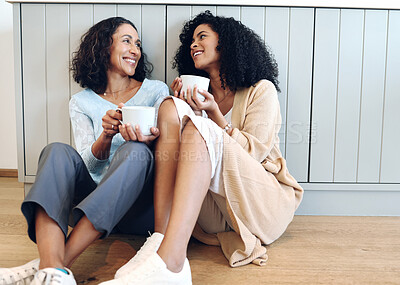 Buy stock photo Love, coffee and mother in conversation with her daughter on the floor in the kitchen of the family home. Happy, smile and adult female child talking to her mature mom while drinking a cup of tea.