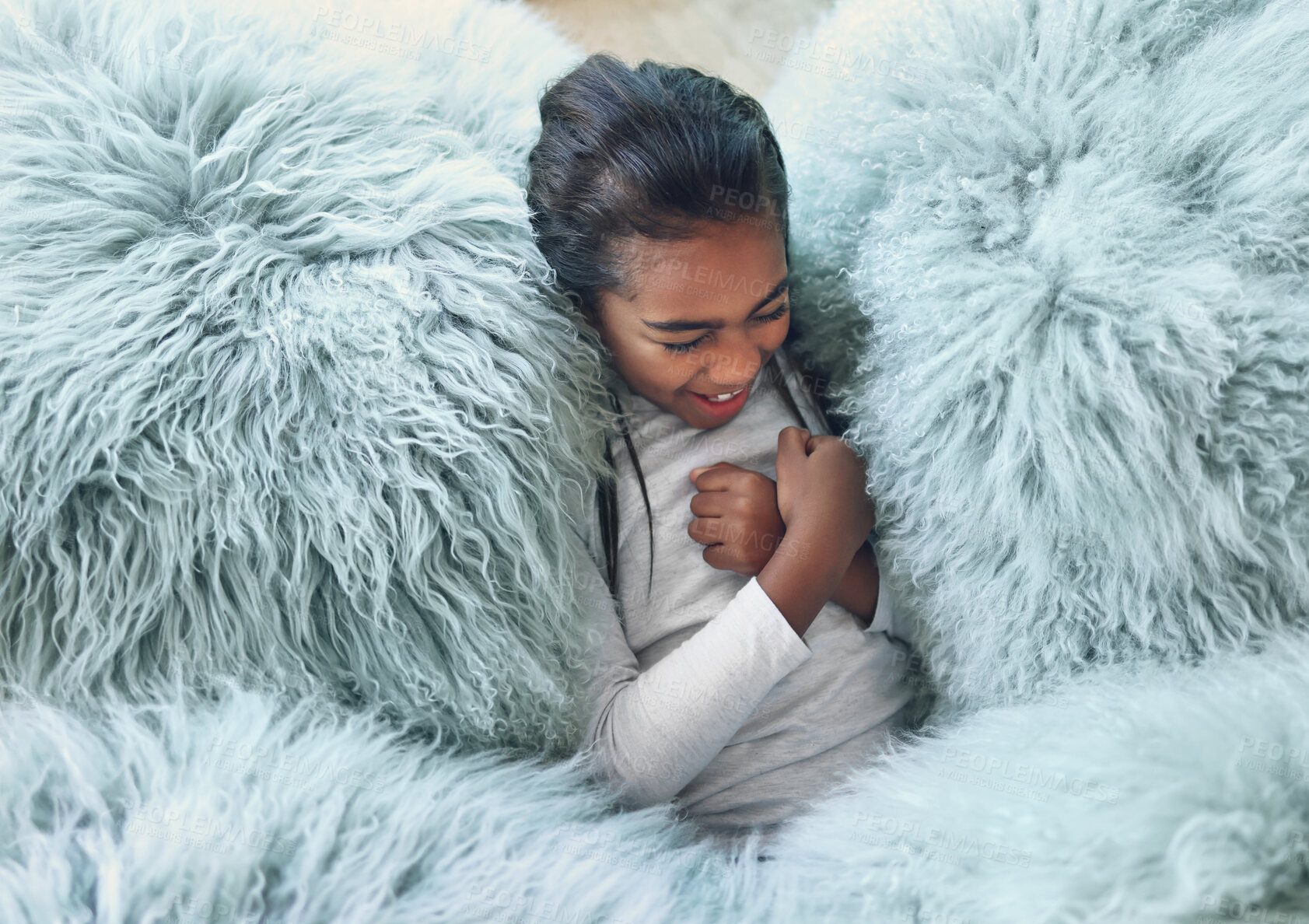 Buy stock photo Comfy, happy and girl on a pillow to relax, playing and laughing from above in a house. Smile, laughing and carefree child cozy in the lounge being playful, funny and relaxing on a soft sofa