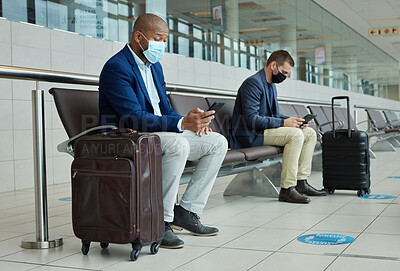 Buy stock photo Social distance, suitcase and businessmen waiting in the airport and networking with cellphone. Face mask, luggage and professional male employees sitting with travel restrictions browsing on a phone