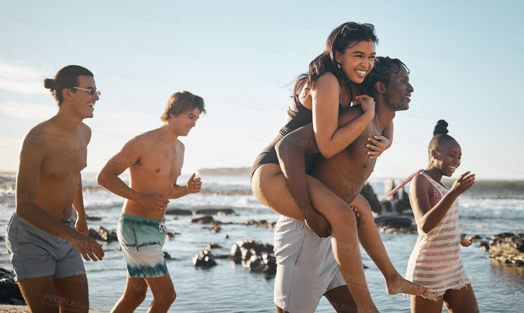 Buy stock photo People, laughing or piggyback by beach, ocean or sea in social gathering, group vacation trust or summer holiday. Smile, happy or diversity friends carrying women in travel fun, bonding or comic game