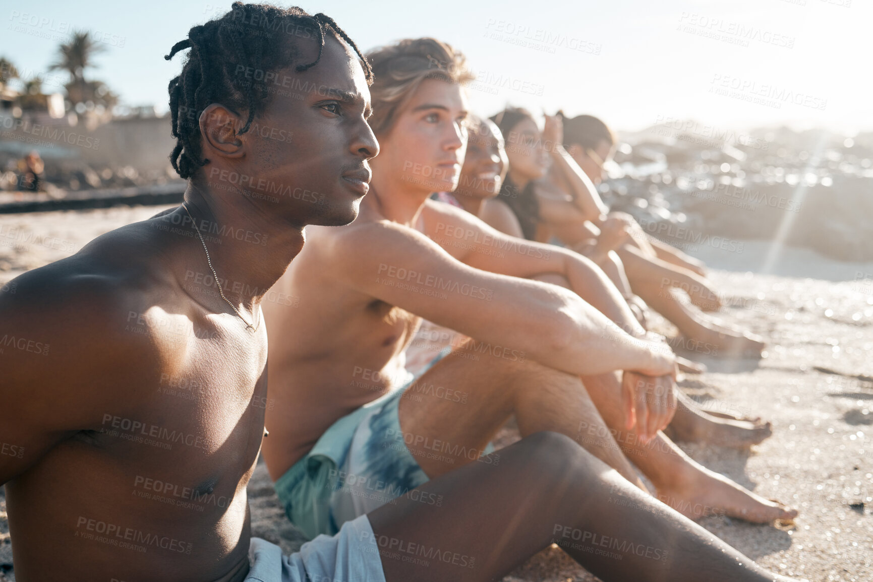 Buy stock photo Black man, bonding and sitting on beach sand with friends in summer holiday, vacation break or community travel. Relax, diversity and people in swimsuit by sea for nature freedom or social gathering