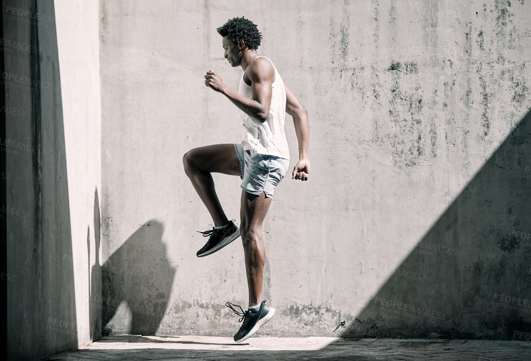 Buy stock photo Exercise, fitness and black man jump in city for health, wellness and energy against wall mockup. Sports, training and male athlete jumping, workout or exercising for endurance, practice or strength.